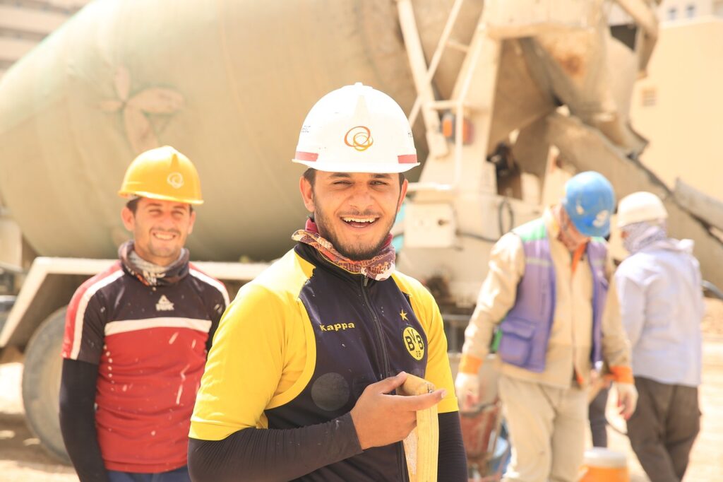 Three construction workers with hard hards on and machinery in background