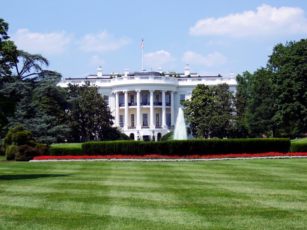 Whitehouse in background surrounded by trees and large green lawn